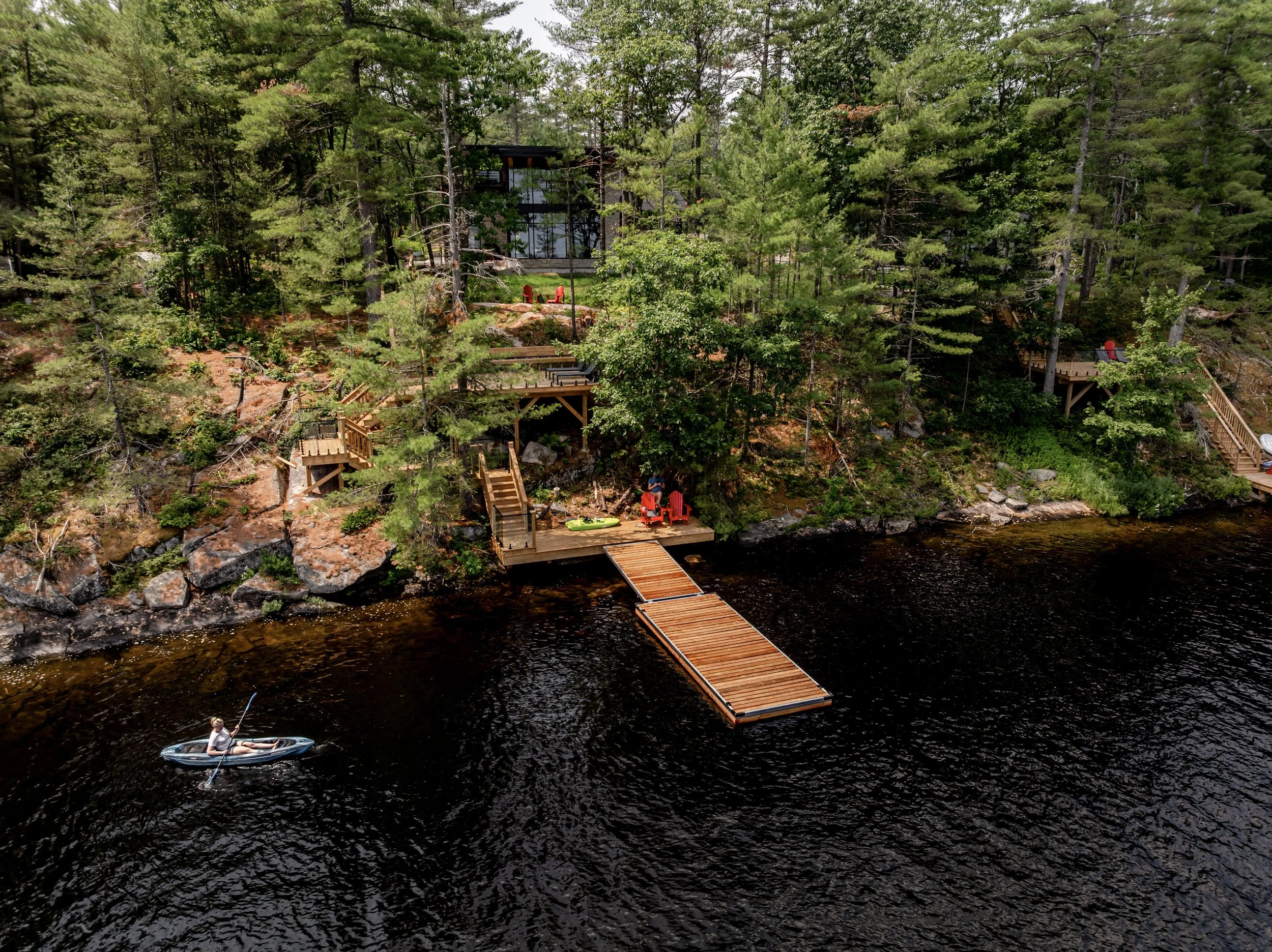 Person kayaking on Muldrew Lake in Gravenhurst beside a large Muskoka waterfront cottage