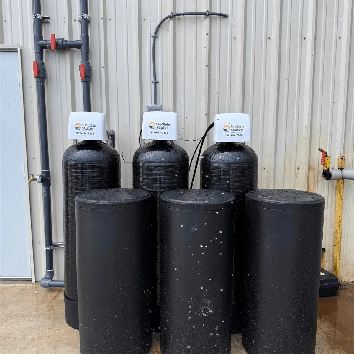Three SunState Water whole-home water softener systems installed outside a Florida building