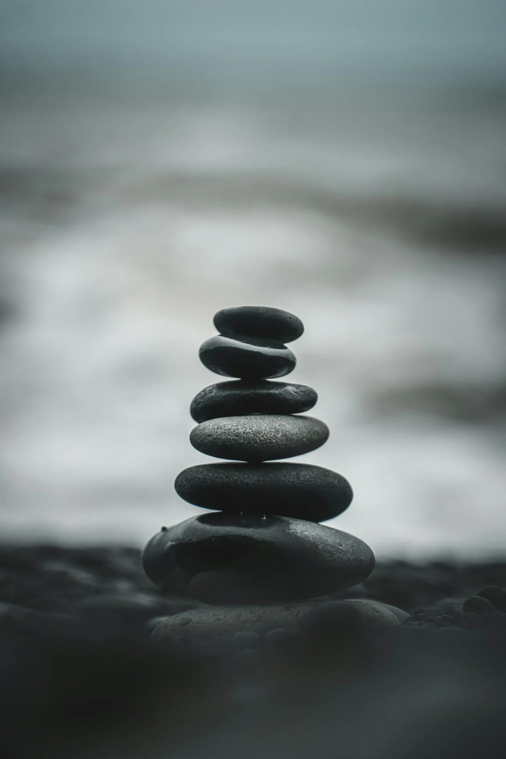 Stacked smooth black stones on a flat surface with a blurred background.