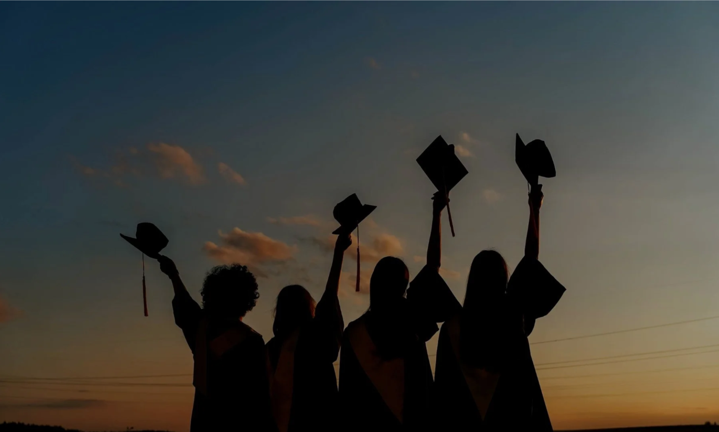 shadow of graduating students in graduation gowns throwing their caps in the air