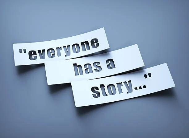Paper strips with the quote 'everyone has a story...' on a gray background.