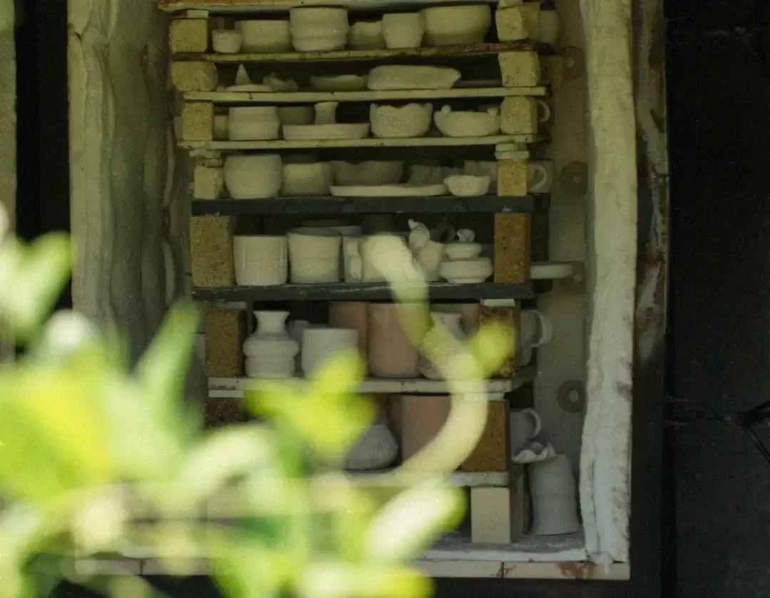 A shelf filled with various unfinished ceramic pottery pieces in different shapes and sizes. A gift handmade in Indonesia