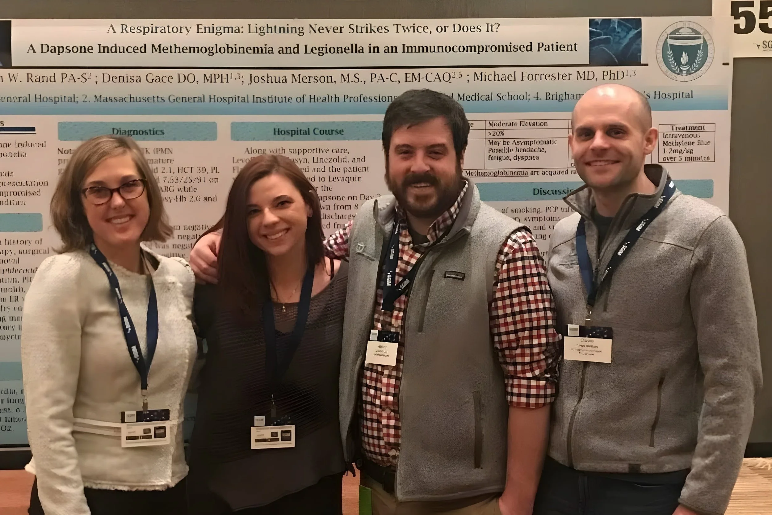 Megan Rand, Sylvia Brandenberg, Harrison Keyes, and Dan McGuire posing in front of a display of medical research.