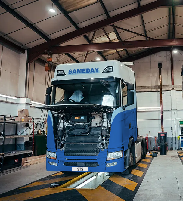A blue and white semi-truck inside a workshop with its hood open for maintenance or repair.