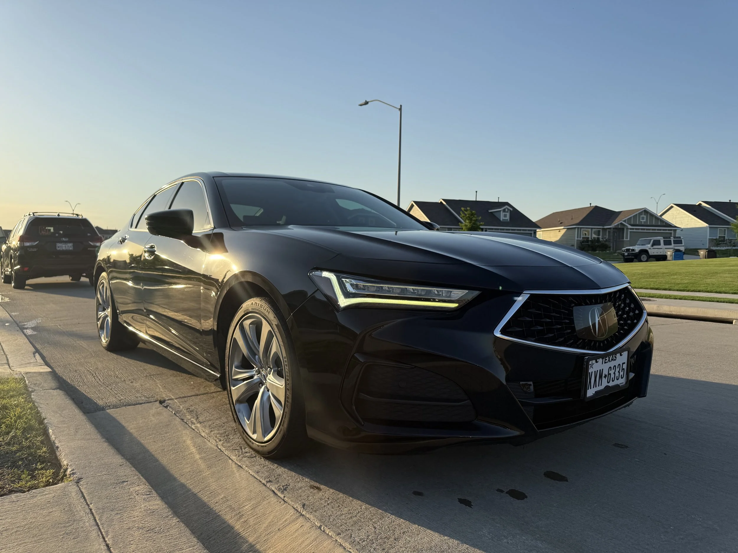 Exterior view of a freshly washed black newer model Acura TLX.
