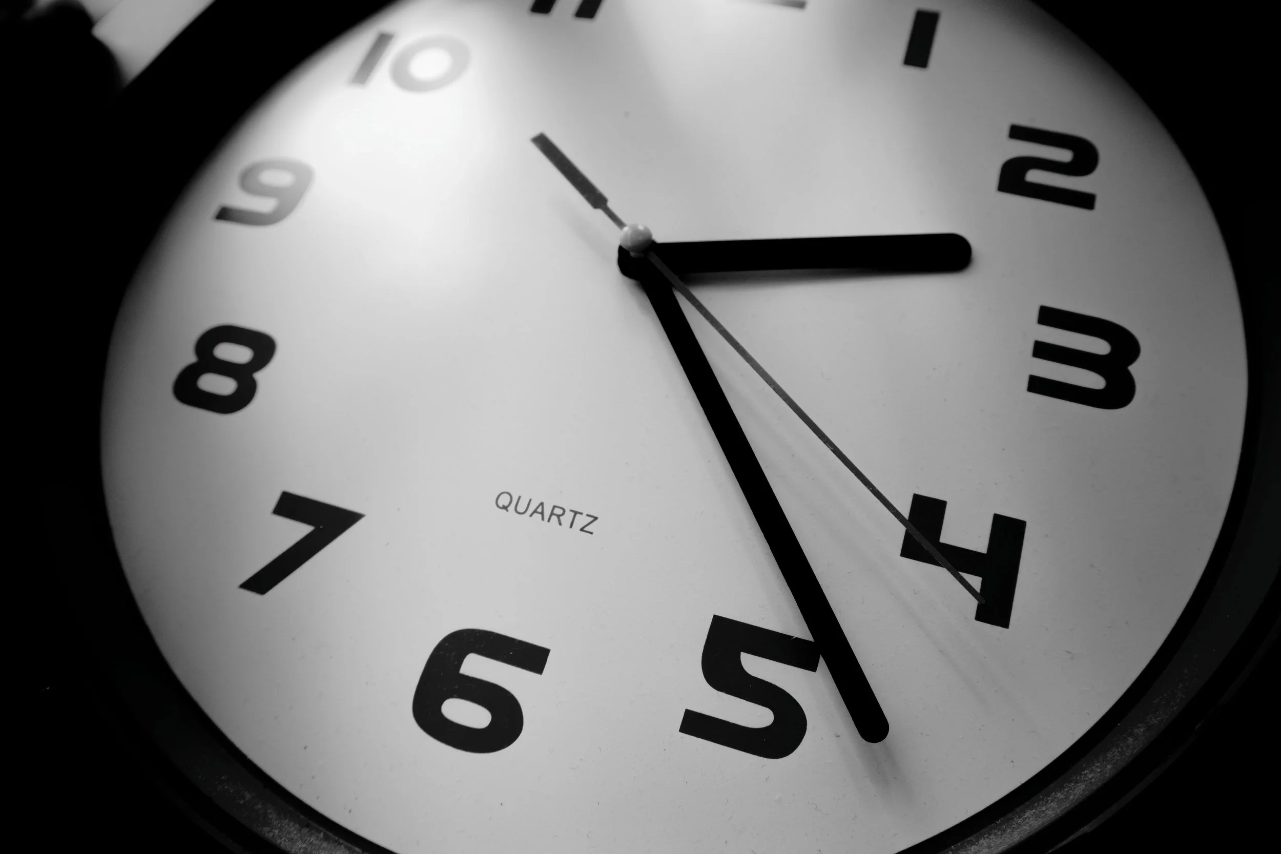 Close-up of an analog clock showing the time as 2:49 with a white face and black numbers. The clock has a black hour hand, minute hand, and a thin second hand.