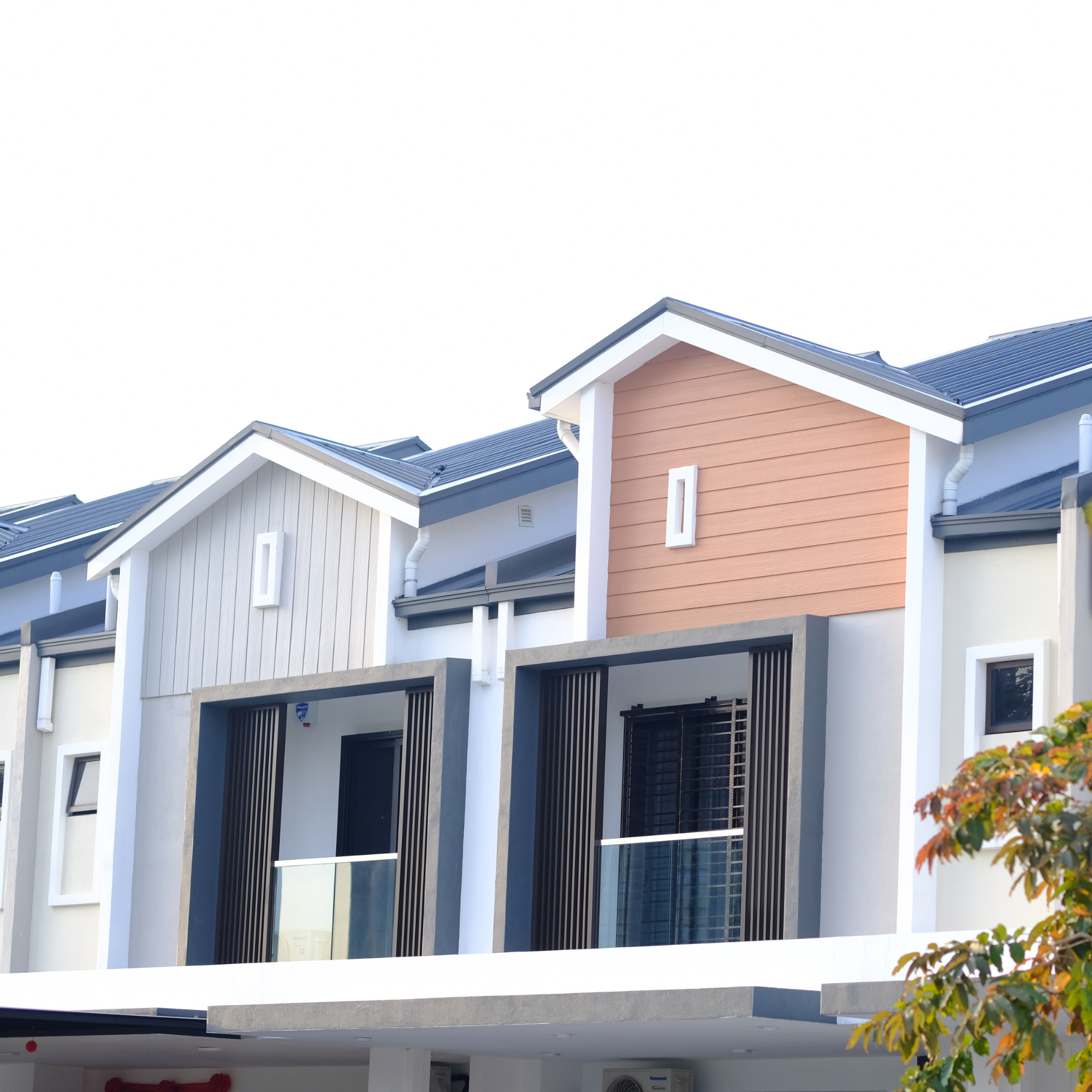 Colorful house with a blue metal roof and an orange exterior wall, featuring white trim and vertical slats, under a clear sky. Part of a tree with orange leaves is visible in the foreground.