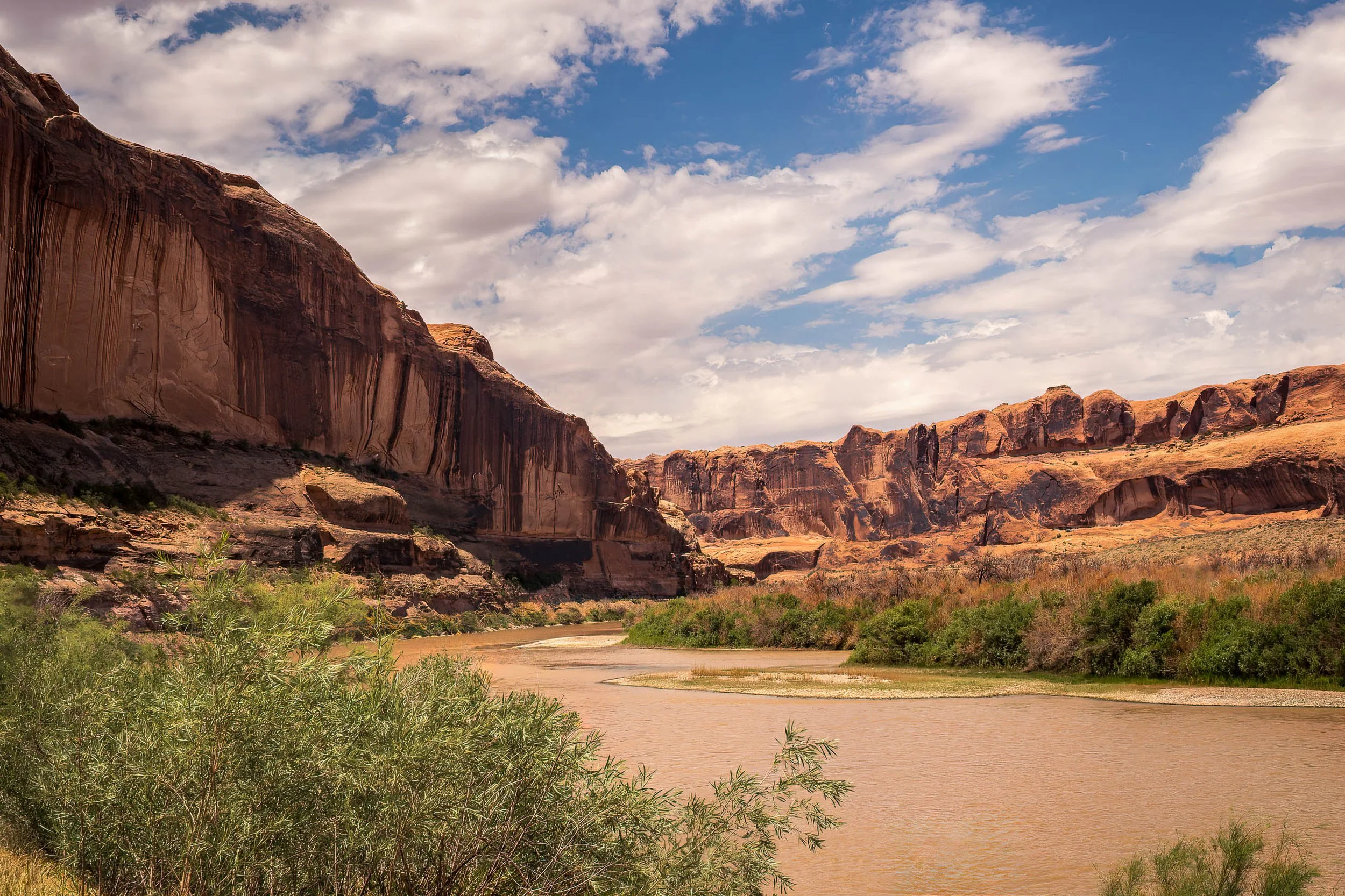 River winding through a red rock canyon beneath towering sandstone cliffs in the American Southwest.