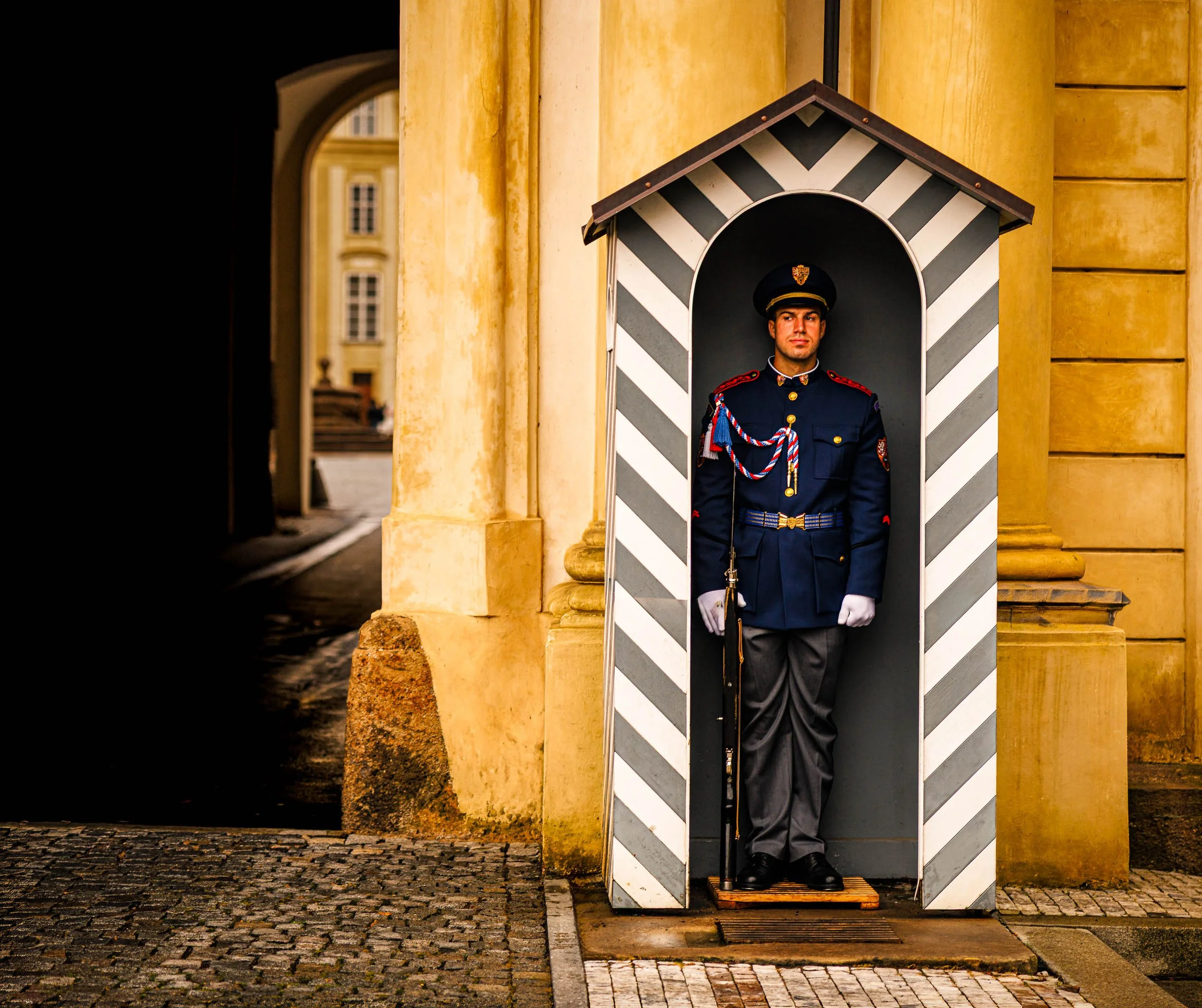 Prague Castle honor guard glancing to the side while standing watch in a striped guard house.