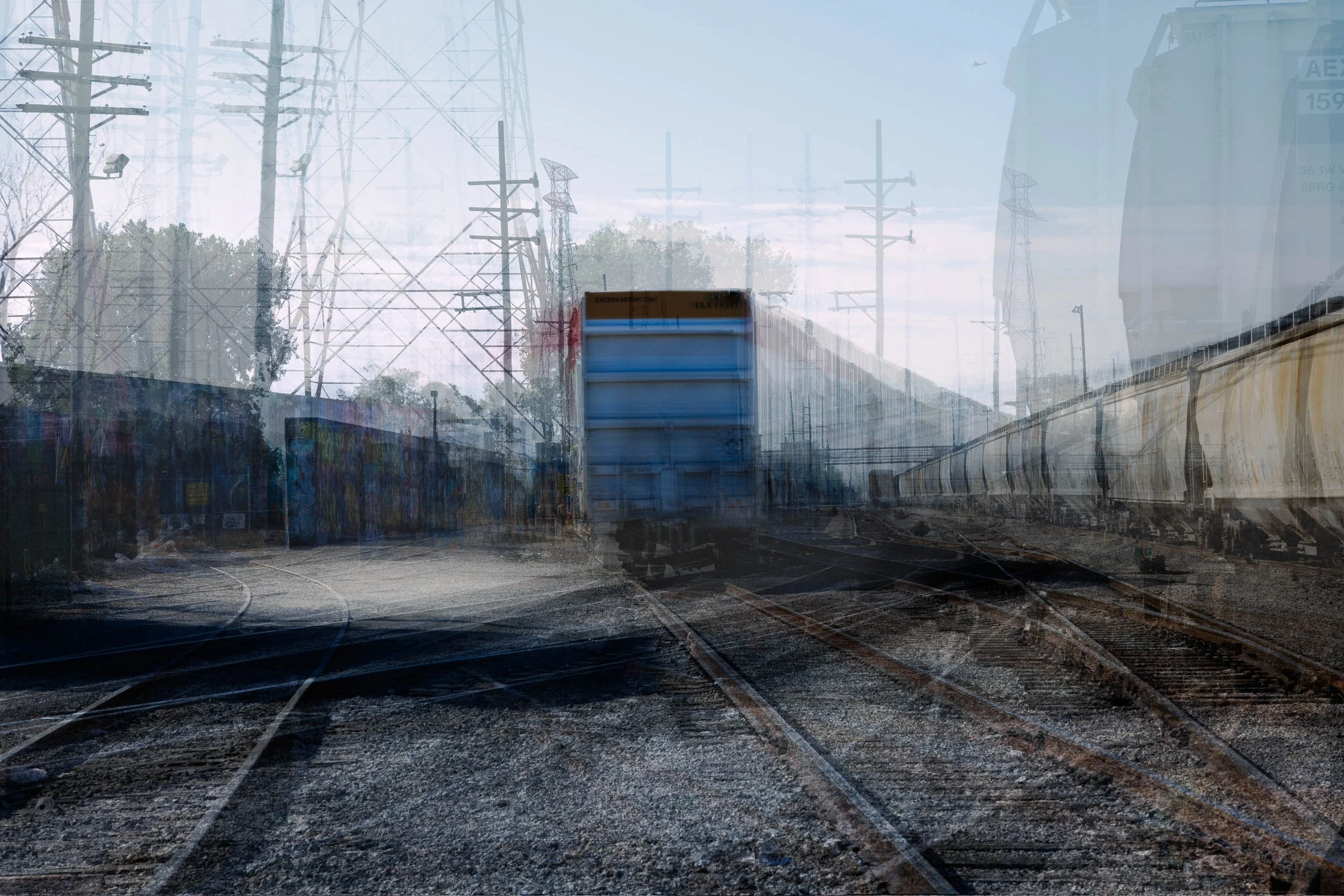 Ghosted blue boxcar, rust-red rails and steel towers in a multiple-exposure rail yard, downtown St. Louis