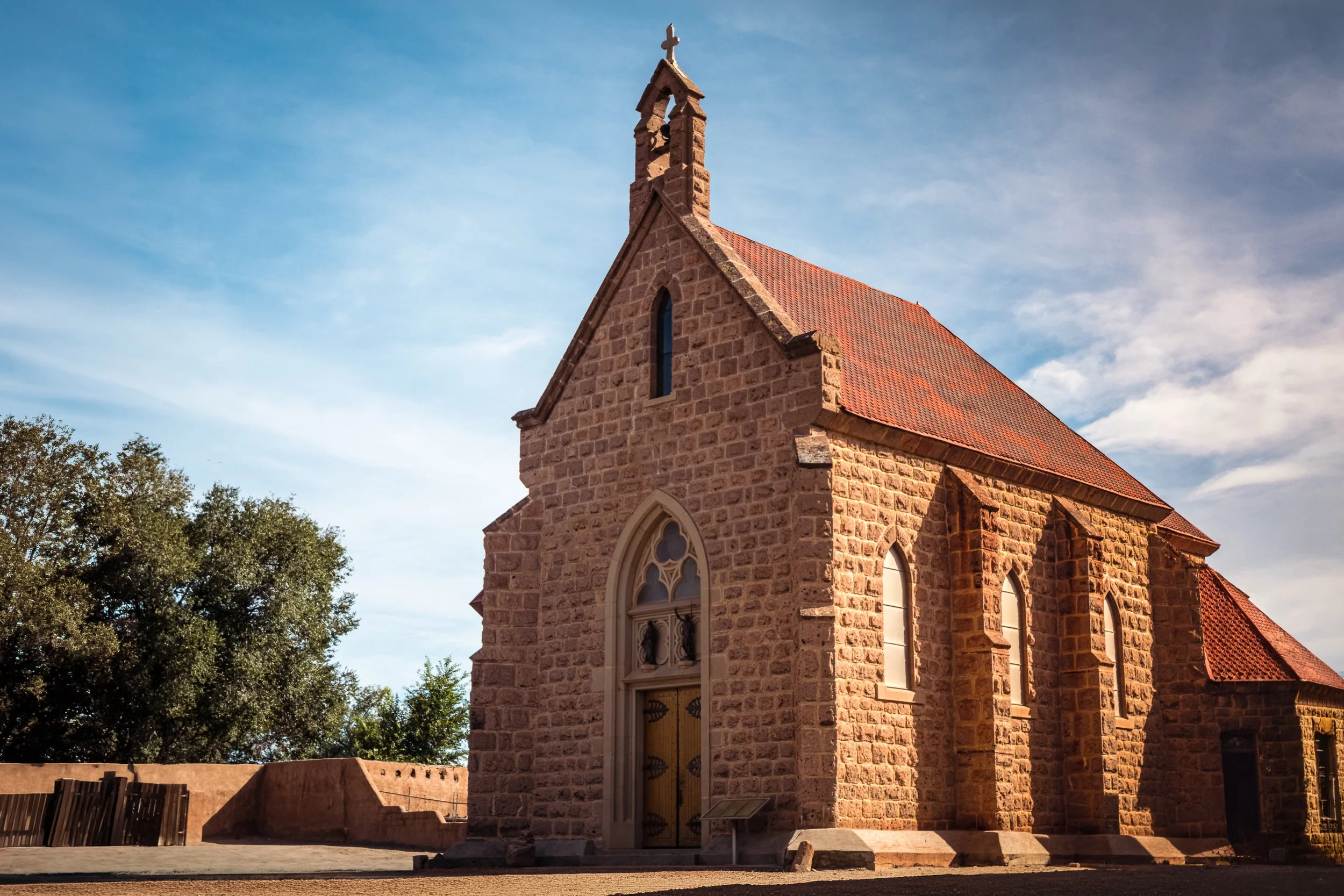 Lava-rock Gothic bell tower and roofline of the Shrine of Our Lady of Lourdes at Ohkay Owingeh Pueblo, New Mexico