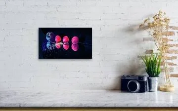 Carried on the Wind – fine art still life photograph of three apricots and a carved stone face lit in warm and cool tones on a reflective black surface