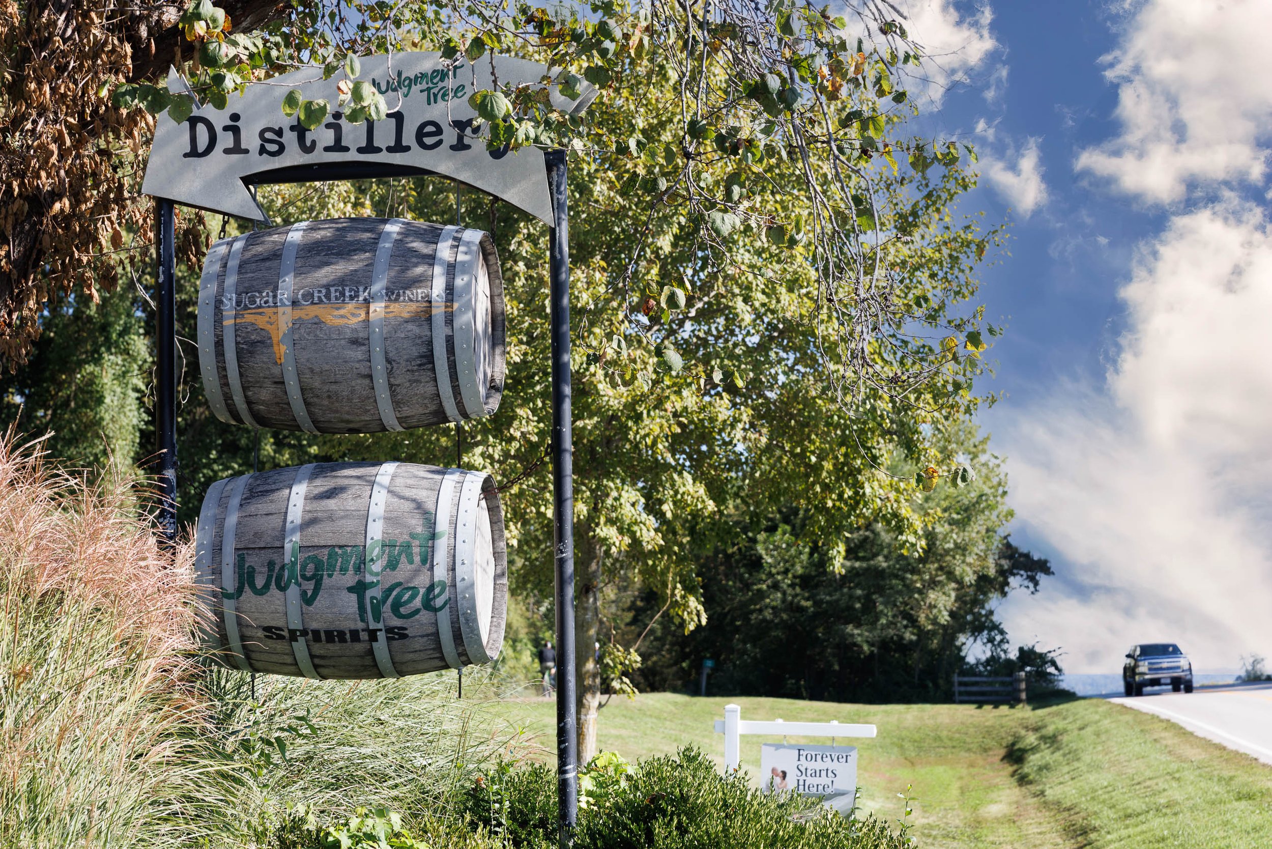 Hanging whiskey barrels and a Distillery sign beside a wedding venue banner in Defiance, Missouri