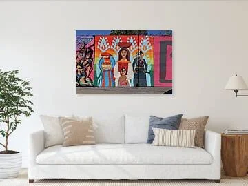 Mural of three standing figures in embroidered dress before horizontal rainbow bands and stepped pale-blue motifs on a wall in St. Louis, the center figure balancing a bowl on her head