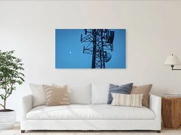 Between Signals – fine art photograph of a crescent moon beside a massive communications tower against a deep blue-violet twilight sky