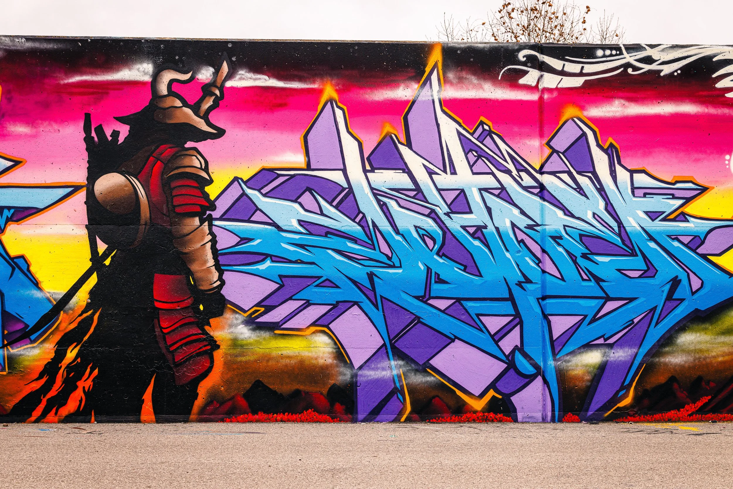 Contemporary Missouri street art photography. A colorful, high-contrast mural of a samurai and graffiti, providing a modern and energetic focal point for urban-inspired corporate or hospitality interior design.