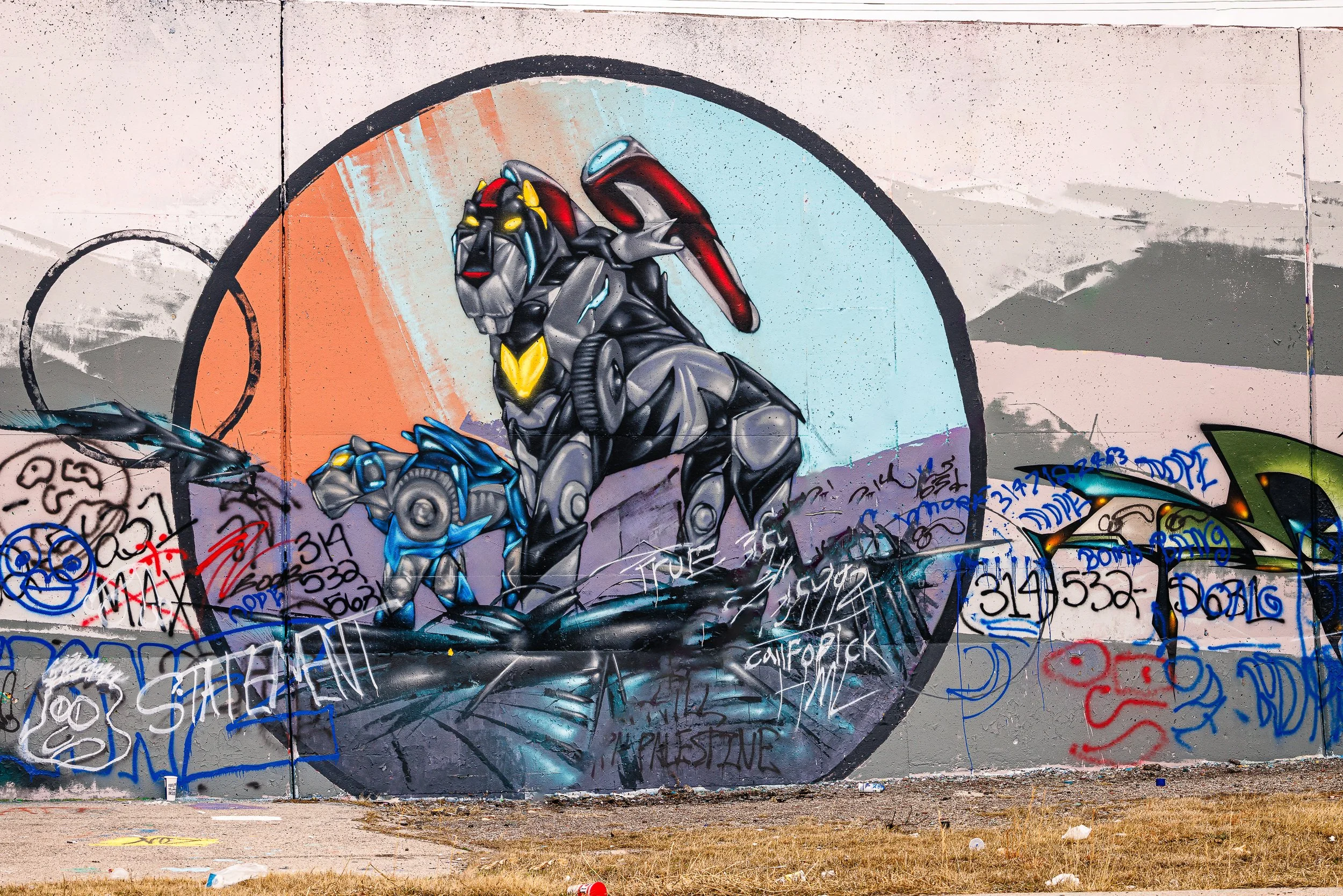 Colorful graffiti mural of a robotic dog with a rainbow in the background, spray-painted on a concrete wall surrounded by tags and graffiti.