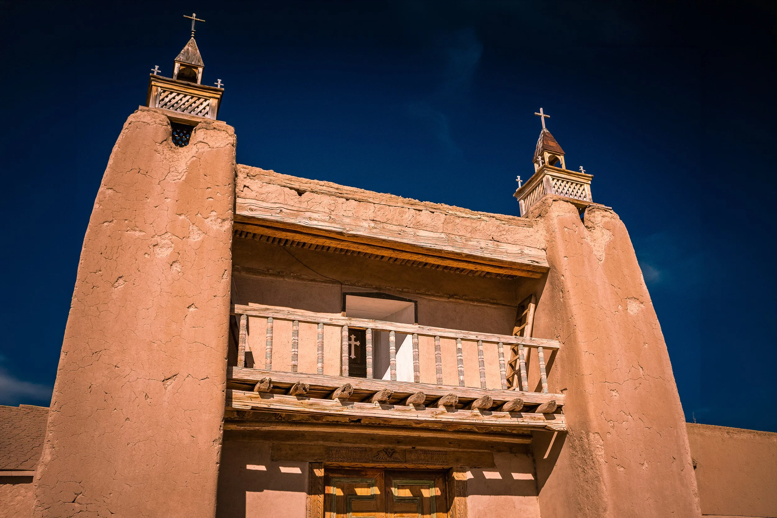 Twin adobe bell towers with wooden crosses at San José de Gracia church, Las Trampas, New Mexico — fine art photography by Robert Niemeier