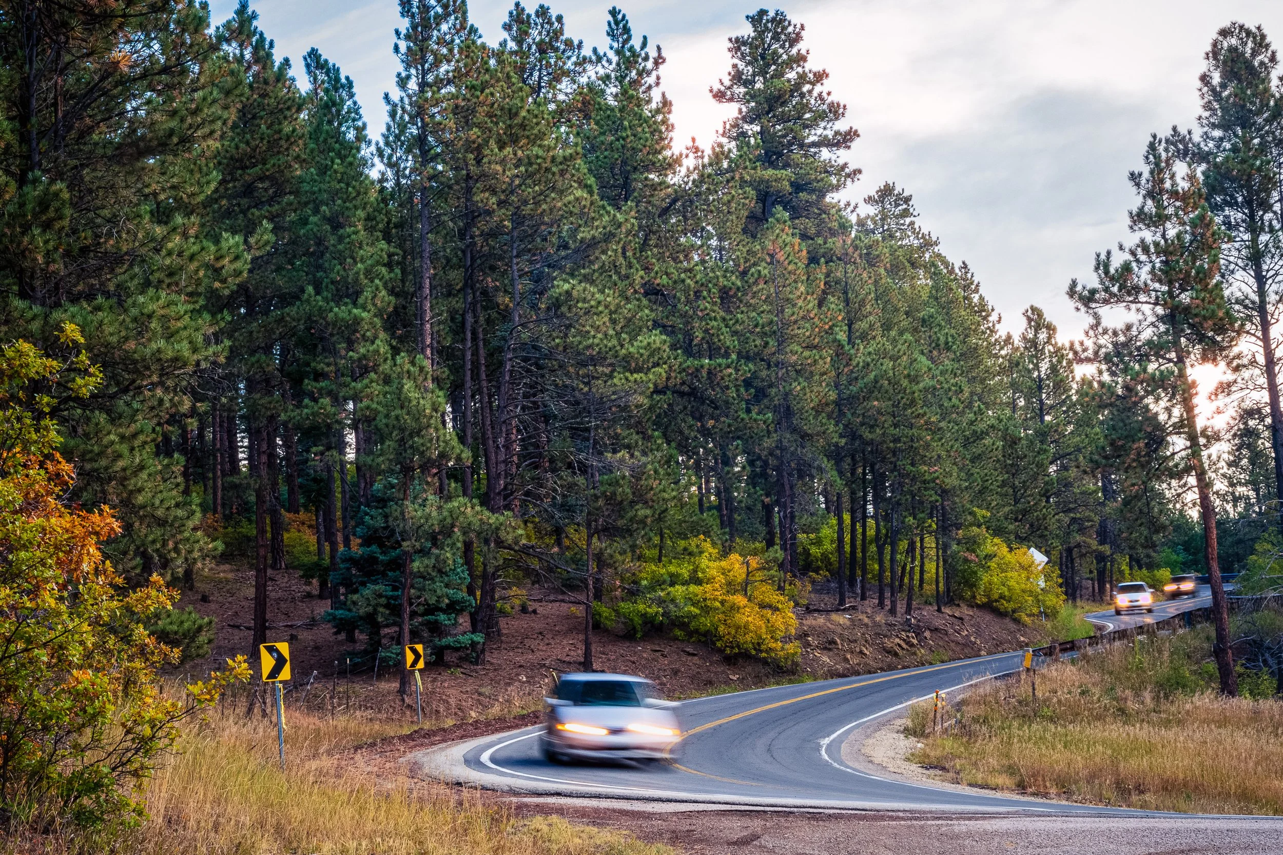 A car in motion blur rounds a mountain S-curve at dusk near the Elliot Barker Trail, Angel Fire, New Mexico