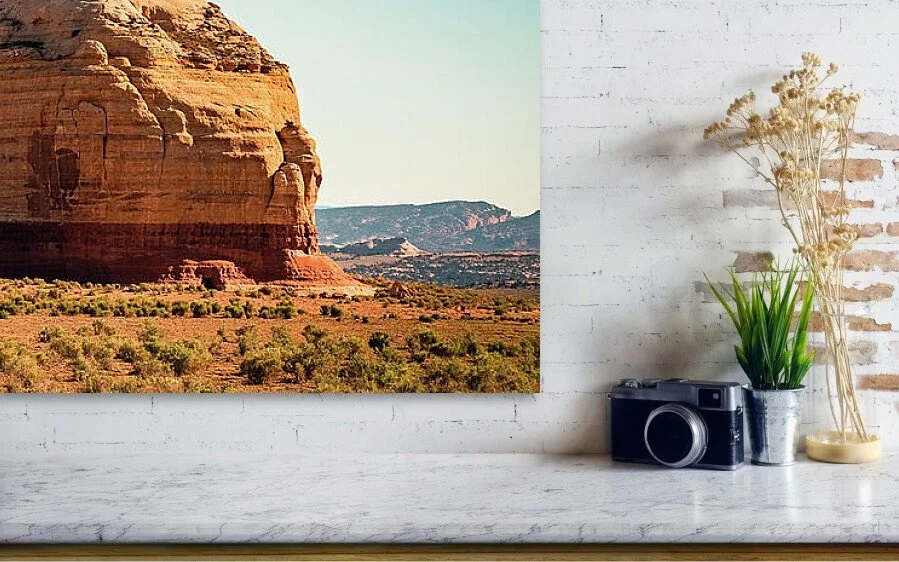 close-up of the layered sandstone in the fine art print above a marble ledge with a camera and a plant