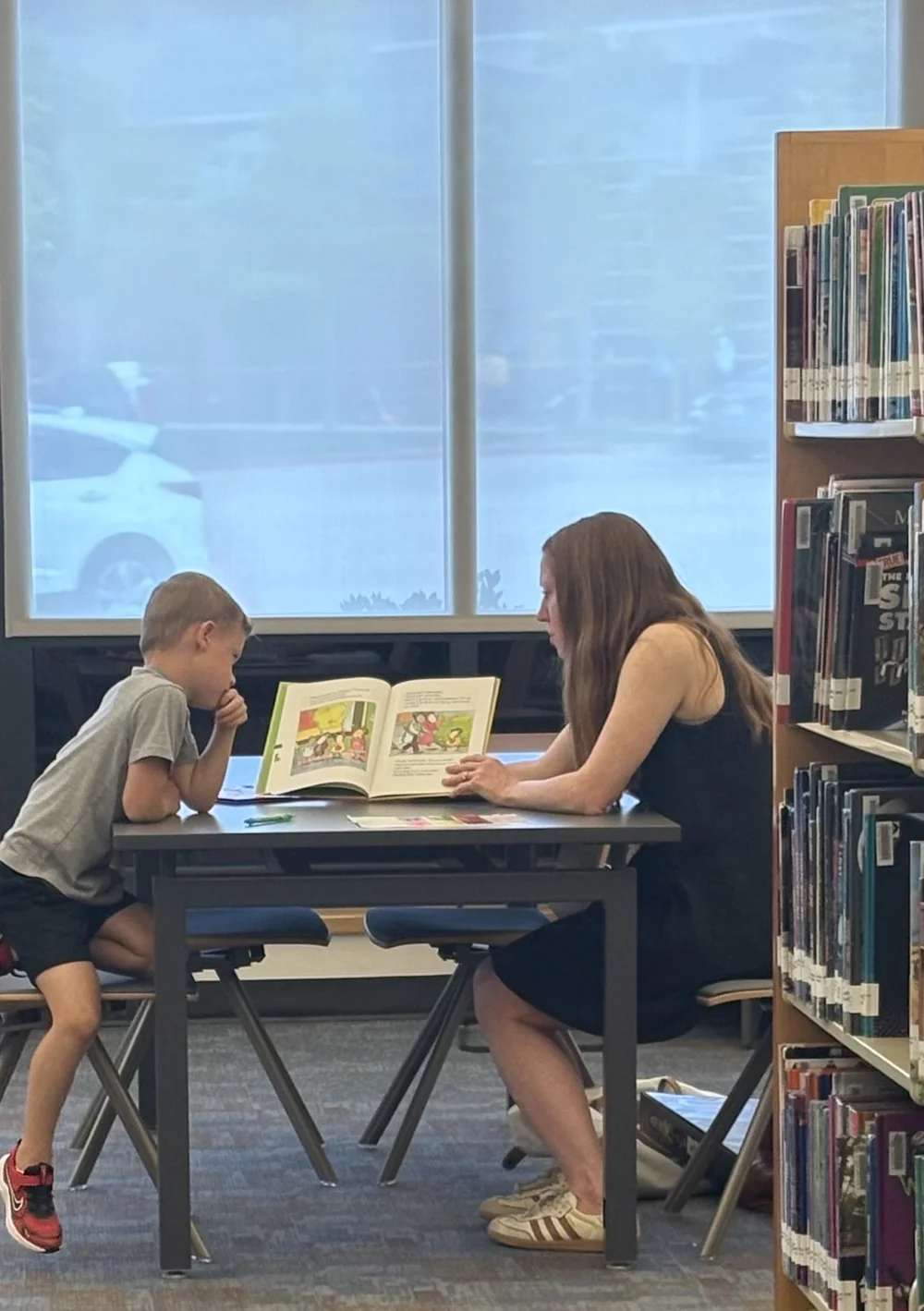 Christy working one-on-one with a student in a library