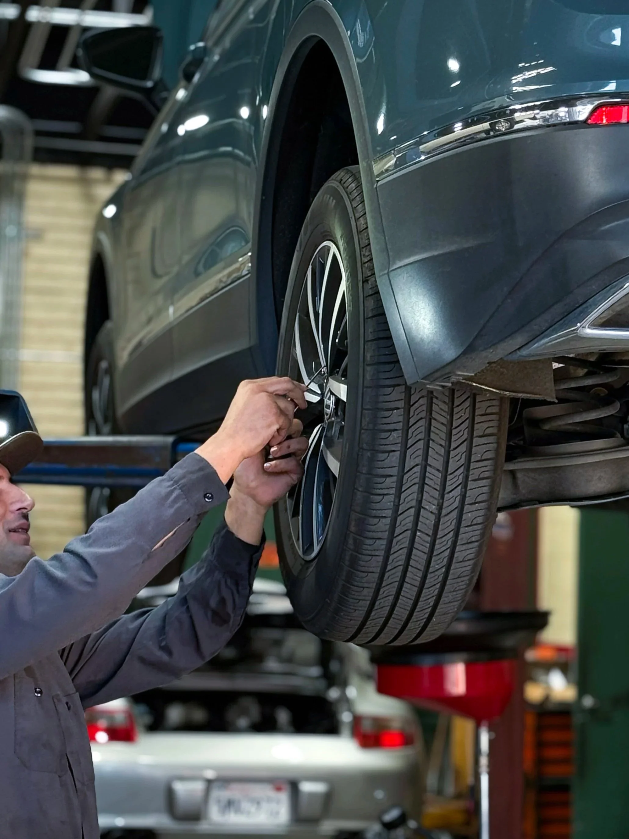 Mechanic inspecting a car's wheel in an automotive repair shop.