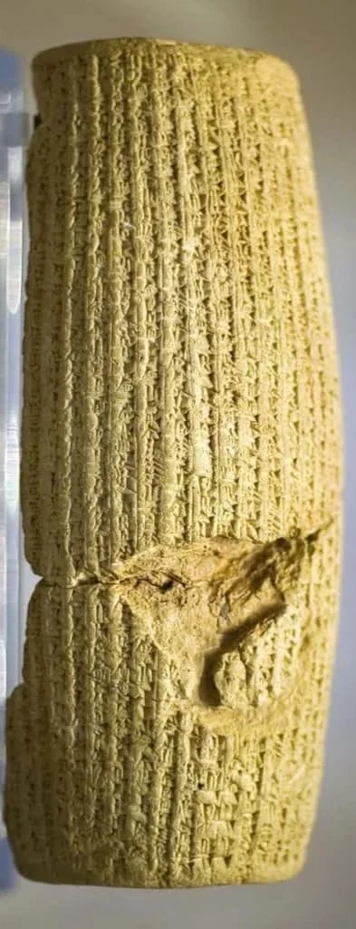 Close-up of an ancient cuneiform clay tablet with impressions and a broken section.