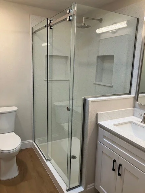 Bathroom with a glass shower enclosure, a white toilet, and a white vanity with a sink.