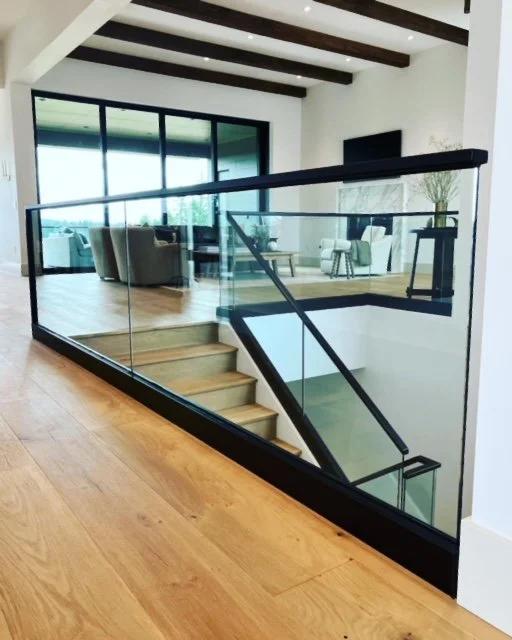 Modern staircase with glass railing in a bright living area.