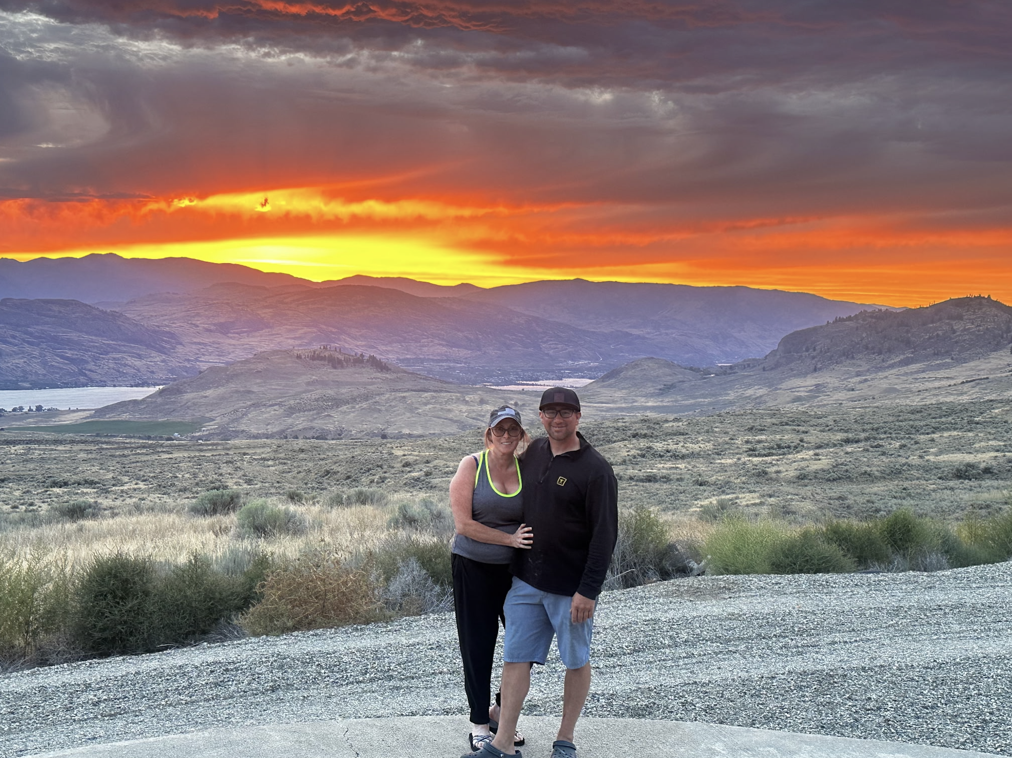 Husband and wife posing in front of a sunset