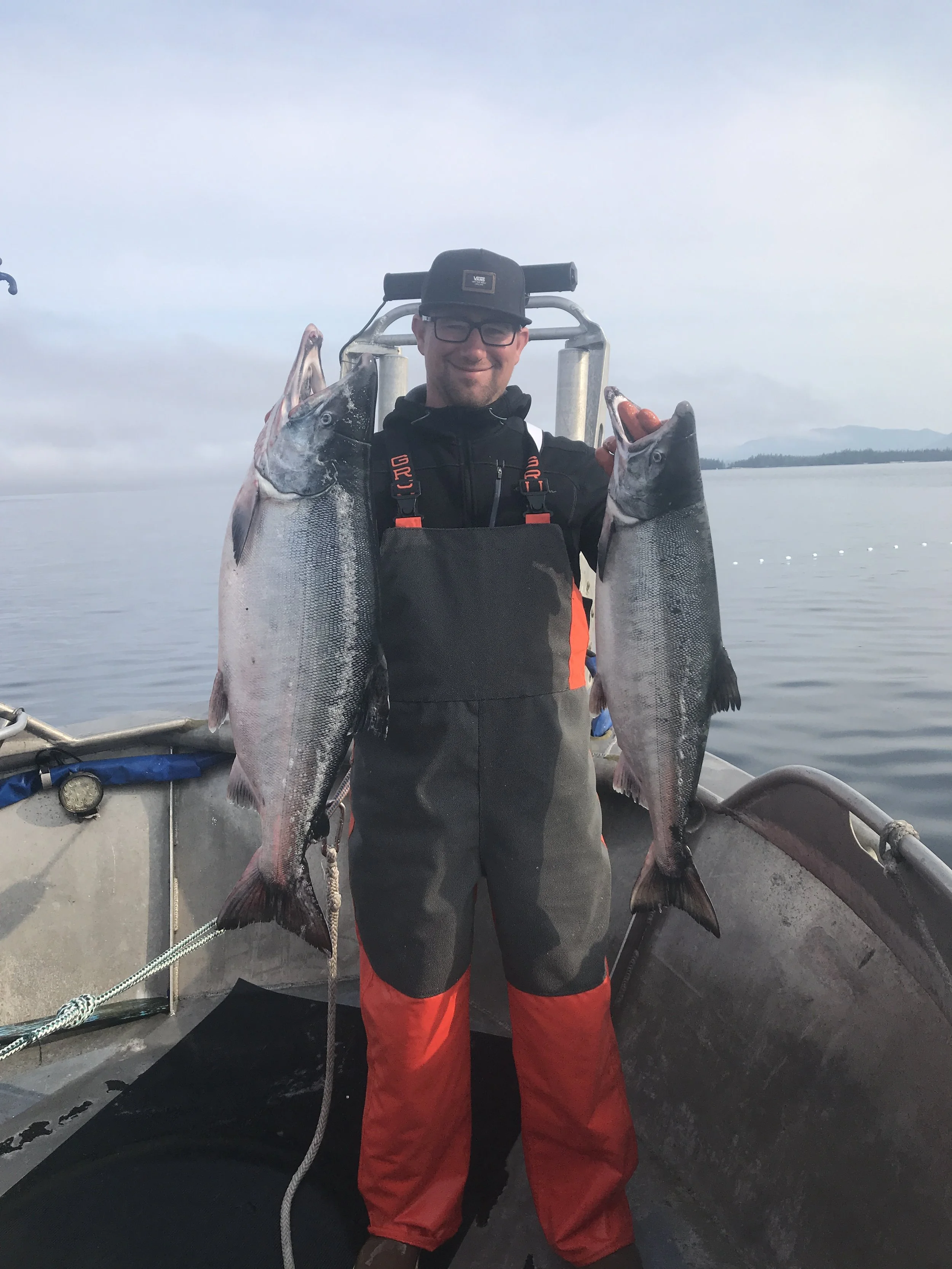 A man holding two large fish on a big boat