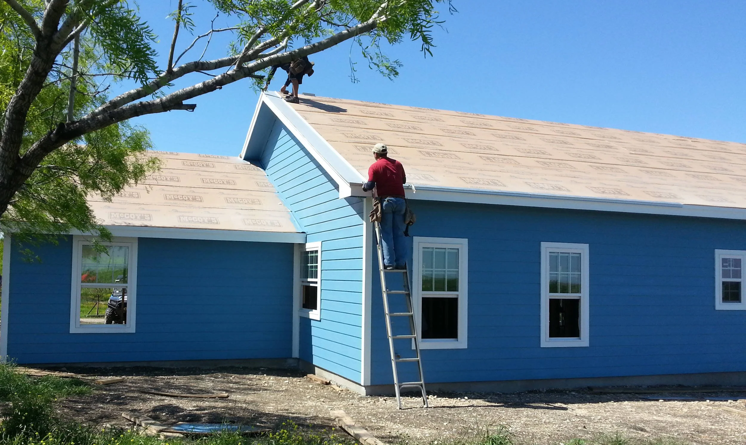 Worker on a ladder installing a metal roof