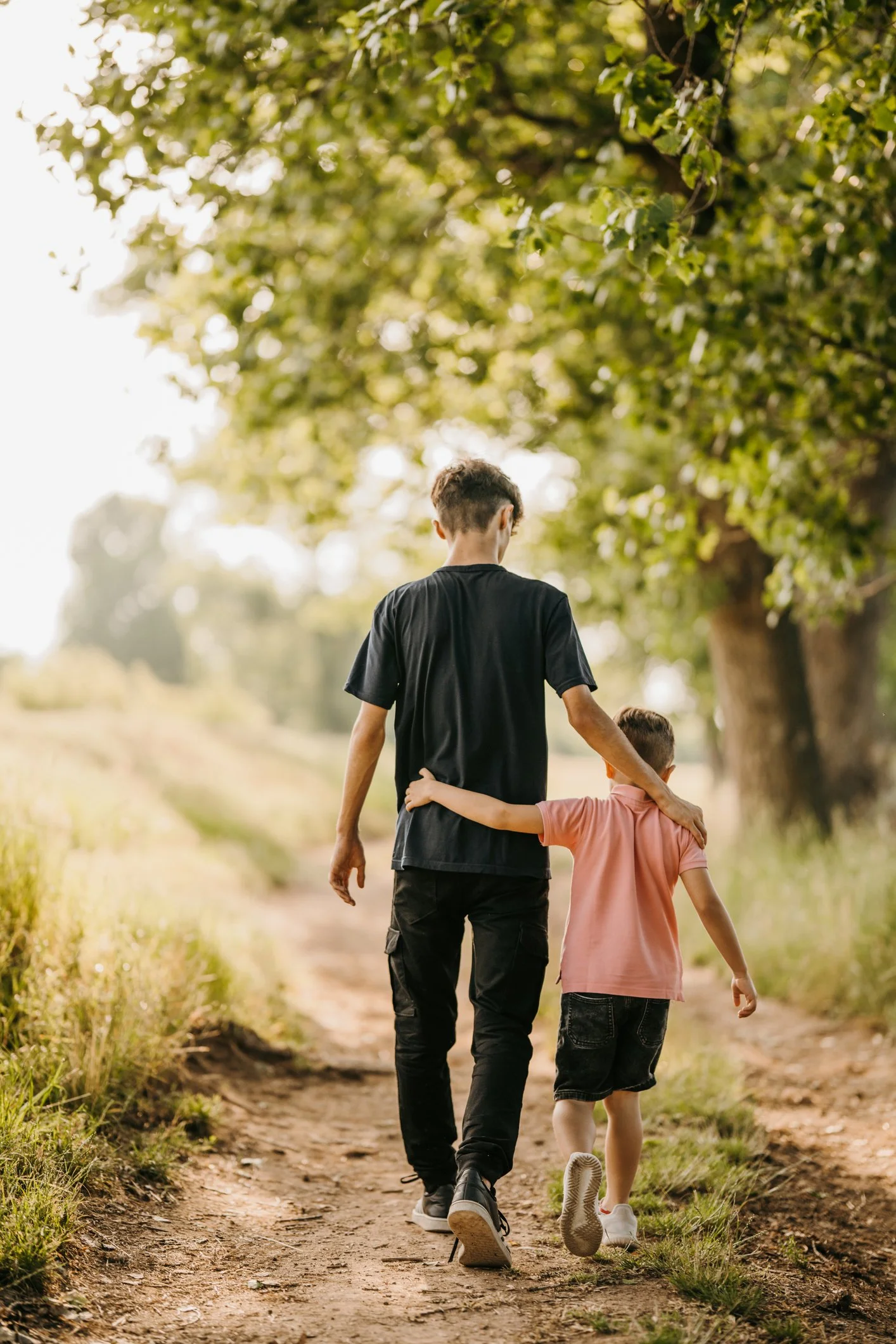 An older boy walking alongside a younger boy, offering support
