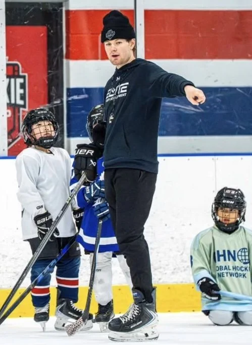 Hockey coach giving instructions to young players on ice rink.