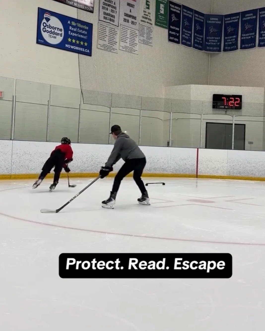 Two people skating on an ice rink, one adult and one child, with a digital clock displaying 7:22 on the wall above them. There are banners and advertisements on the wall behind them, and the text 'Protect. Read. Escape' appears on the edge of the image.