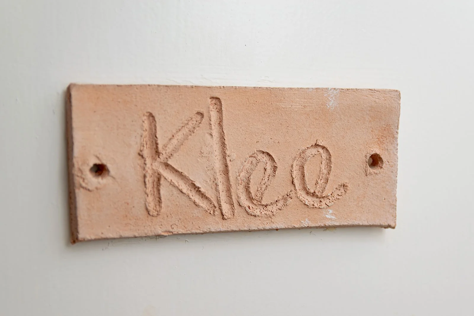 A pinkish-orange brick wall with the word 'Klee' carved into the surface.