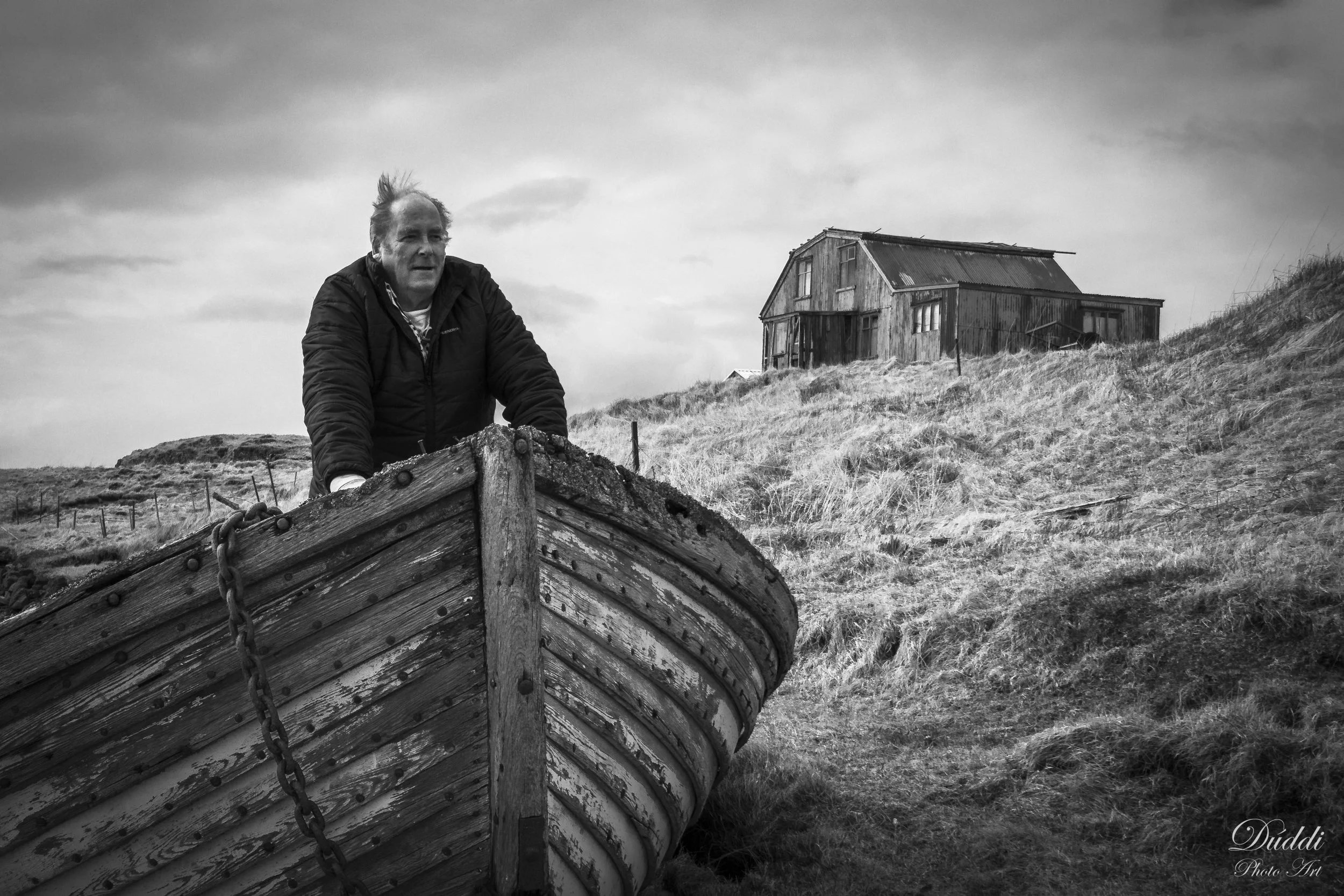Black and white photo of an older man in an old boat in Iceland.