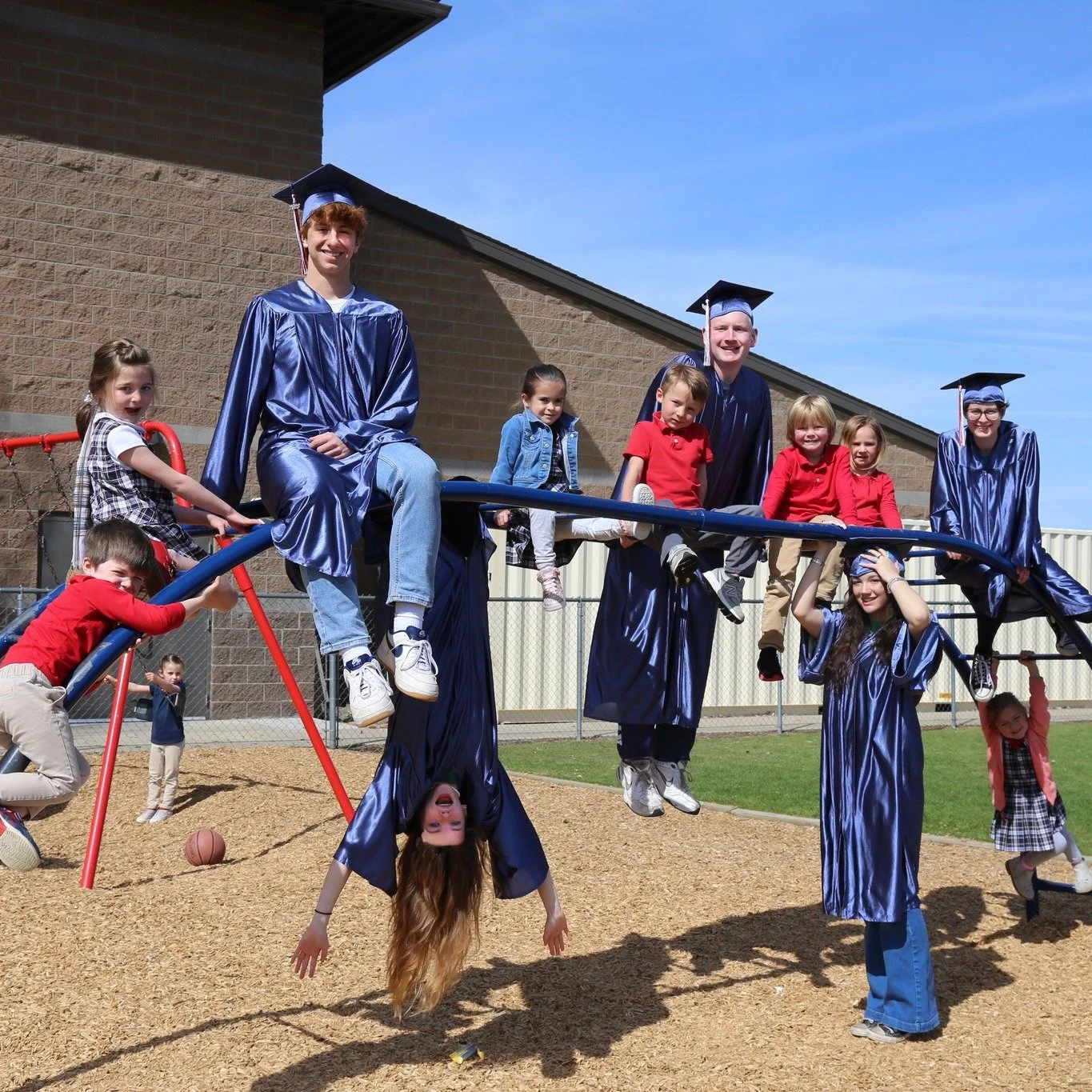 Trinity graduates and young students together on the playground