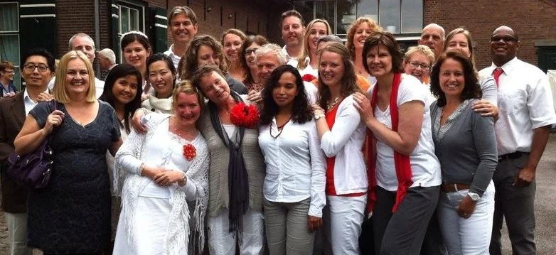 Een grote groep mensen lacht naar de camera.