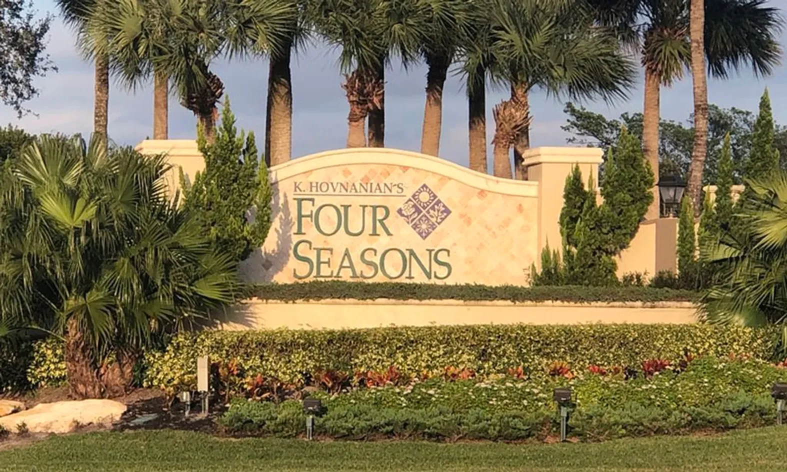 Entrance sign for K. Hovnanian's Four Seasons residential community, surrounded by palm trees and lush landscaping.