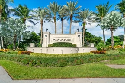 Entrance sign for Valencia Pointe surrounded by palm trees and landscaping.