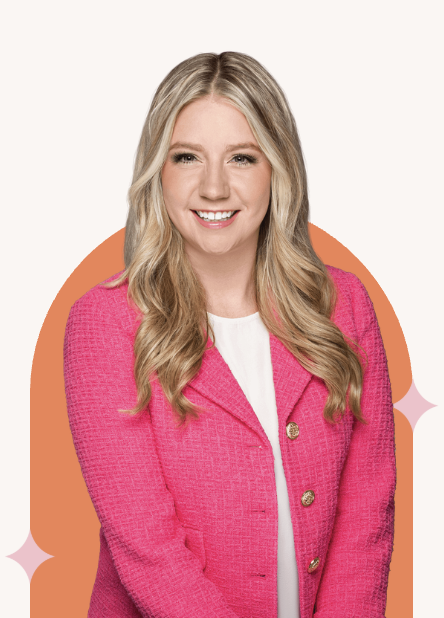 A woman with long blonde hair wearing a pink blazer and white top smiling in front of an orange and pink background.