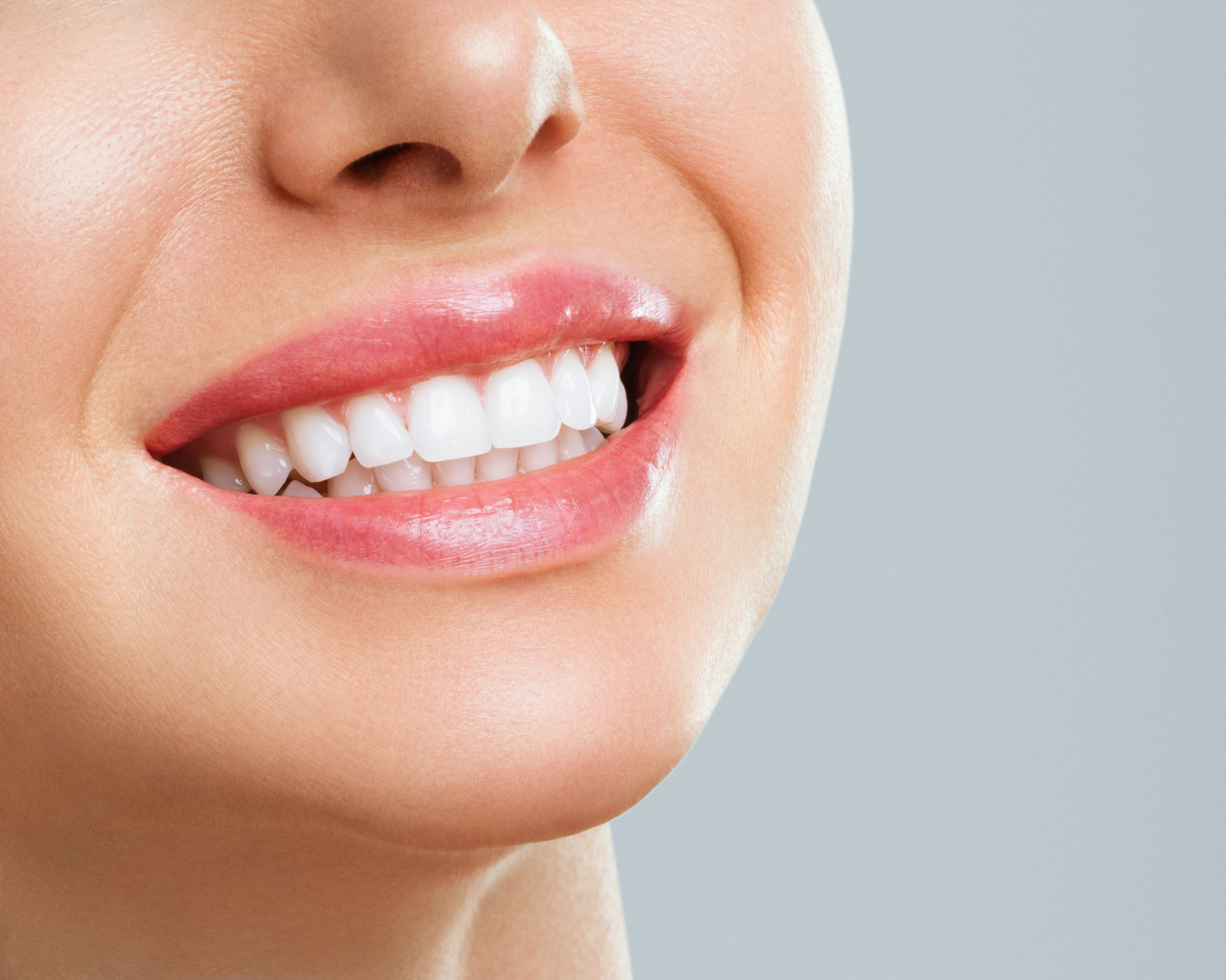 Close-up of a woman smiling, showing her white teeth and pink lips.