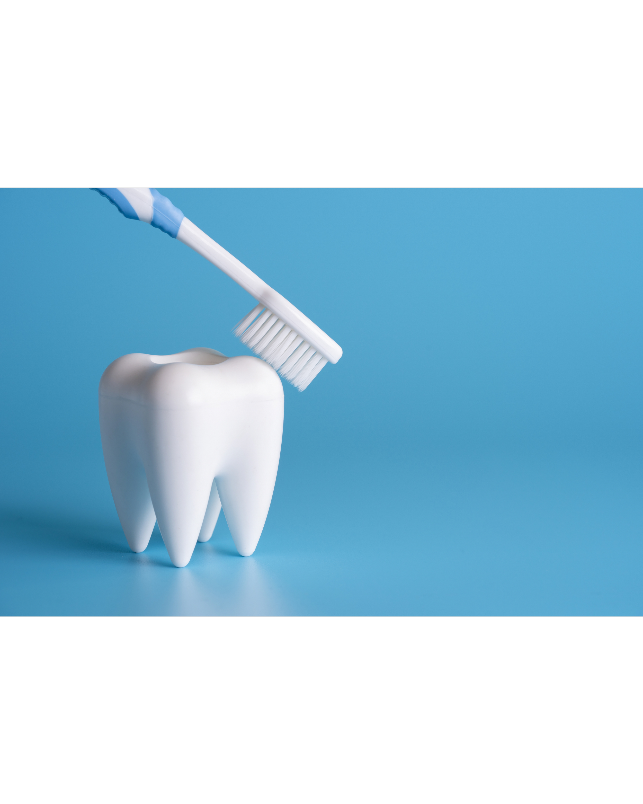 Toothbrush with blue and white handle cleaning a molar tooth with toothpaste on a blue background.