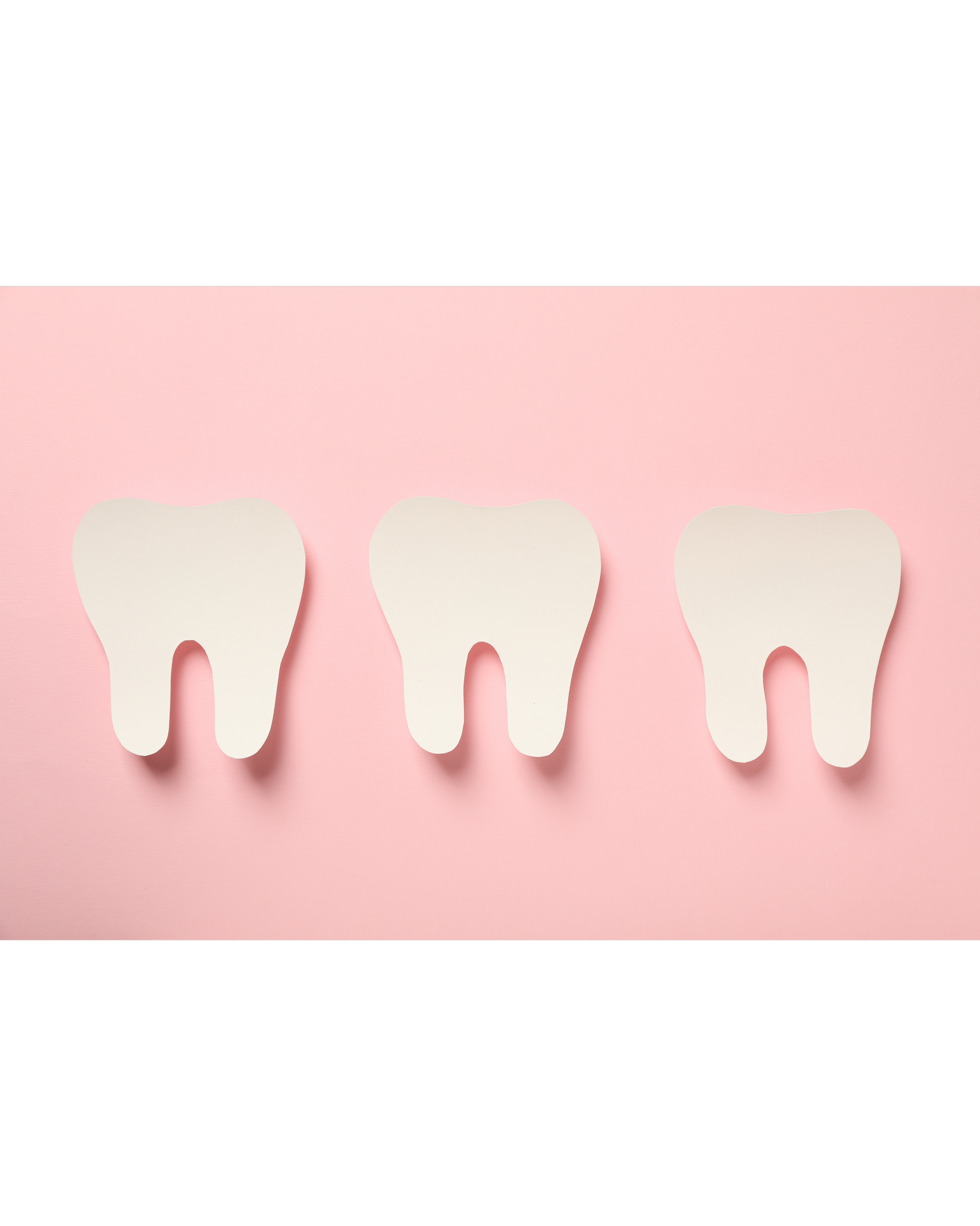 Close-up of four paper teeth cutouts on a pink background with black borders at top and bottom.