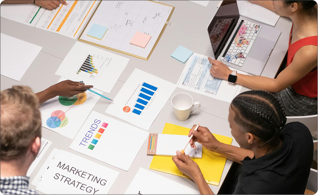 People in a meeting analyzing charts and documents on a white table.