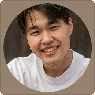 Close-up of a young man smiling with dark hair, wearing a white shirt.