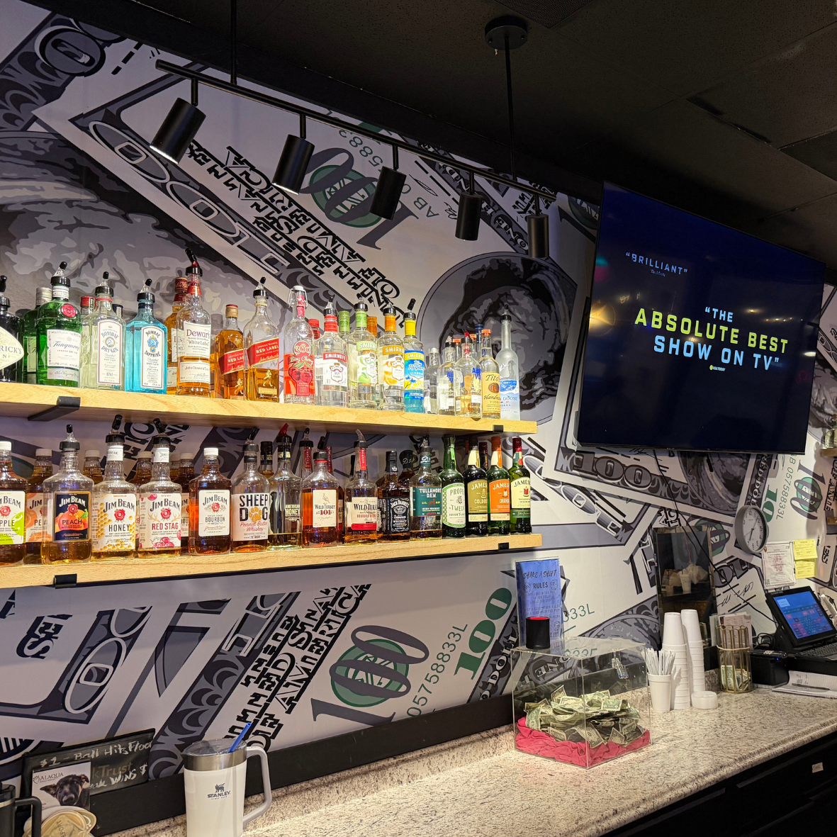 Cash's Liquors liquor rack in a 100 dollar bill wall for social media post and branding