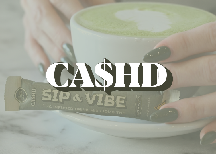 A person with dark manicured nails holding a mug of green matcha latte, with a packet of cash$hop THC-infused drink mix in front of the mug.