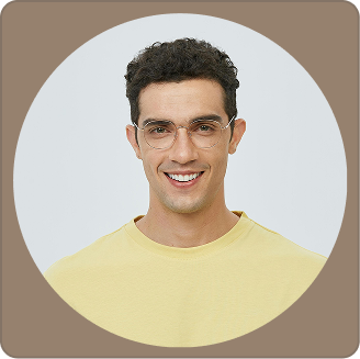 Portrait of a smiling man with dark curly hair, glasses, wearing a yellow shirt, against a neutral background